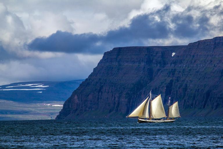 A sailboat sails along the Icelandic coast