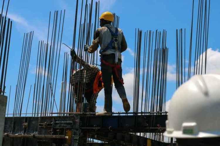 Construction worker in safety gear assembling rebar at a construction site in Iceland, with a backdrop of a clear blue sky. Construction work is one of the top entry-level jobs in Iceland