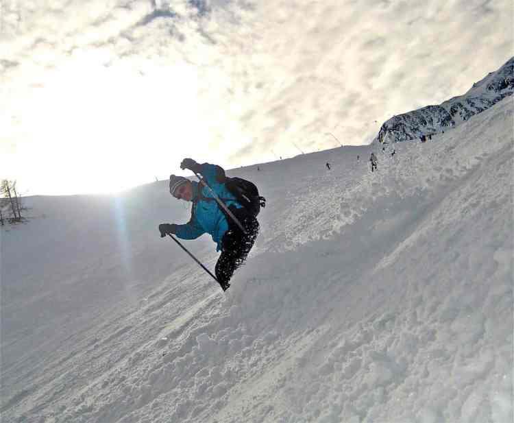 Skier descending a steep snowy slope, demonstrating adventure winter sports and the thrill of skiing, similar to experiences available in Iceland's mountainous landscapes.