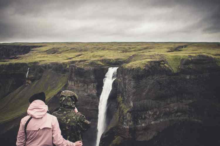 Two people overlooking a waterfall in Iceland, embodying the raw beauty and serene nature of Icelandic wilderness. As an au pair in Iceland you can explore stunning landscapes.